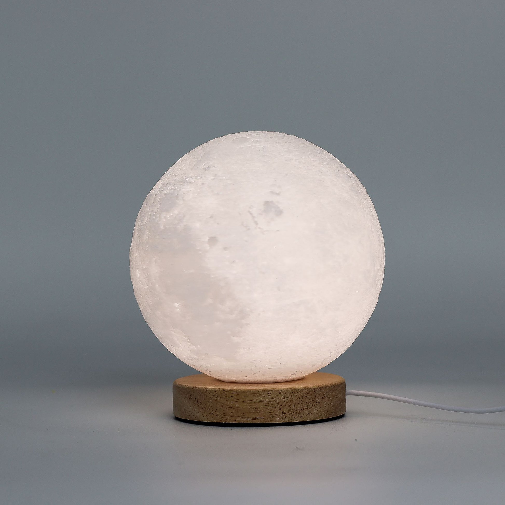 Moon New Wave USB lamp with textured honeycomb surface and crescent moon-inspired shape, warm glow on 3rd brightness setting, placed on wooden base