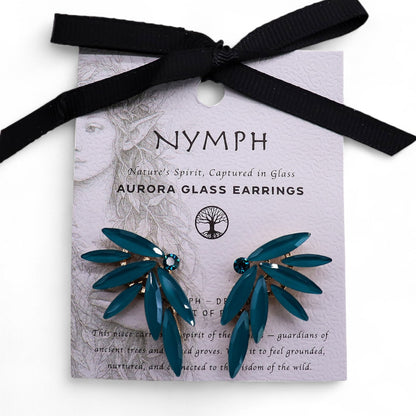 Delicate teal-green fairy wing earrings with translucent vintage glass, glowing softly against moss and forest leaves