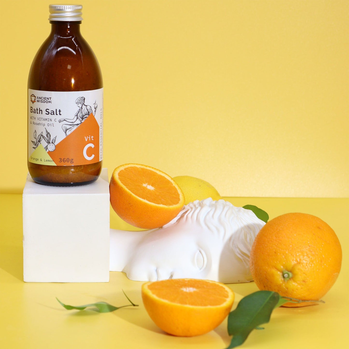 Bath salt bottle with oranges and lemons on a yellow background