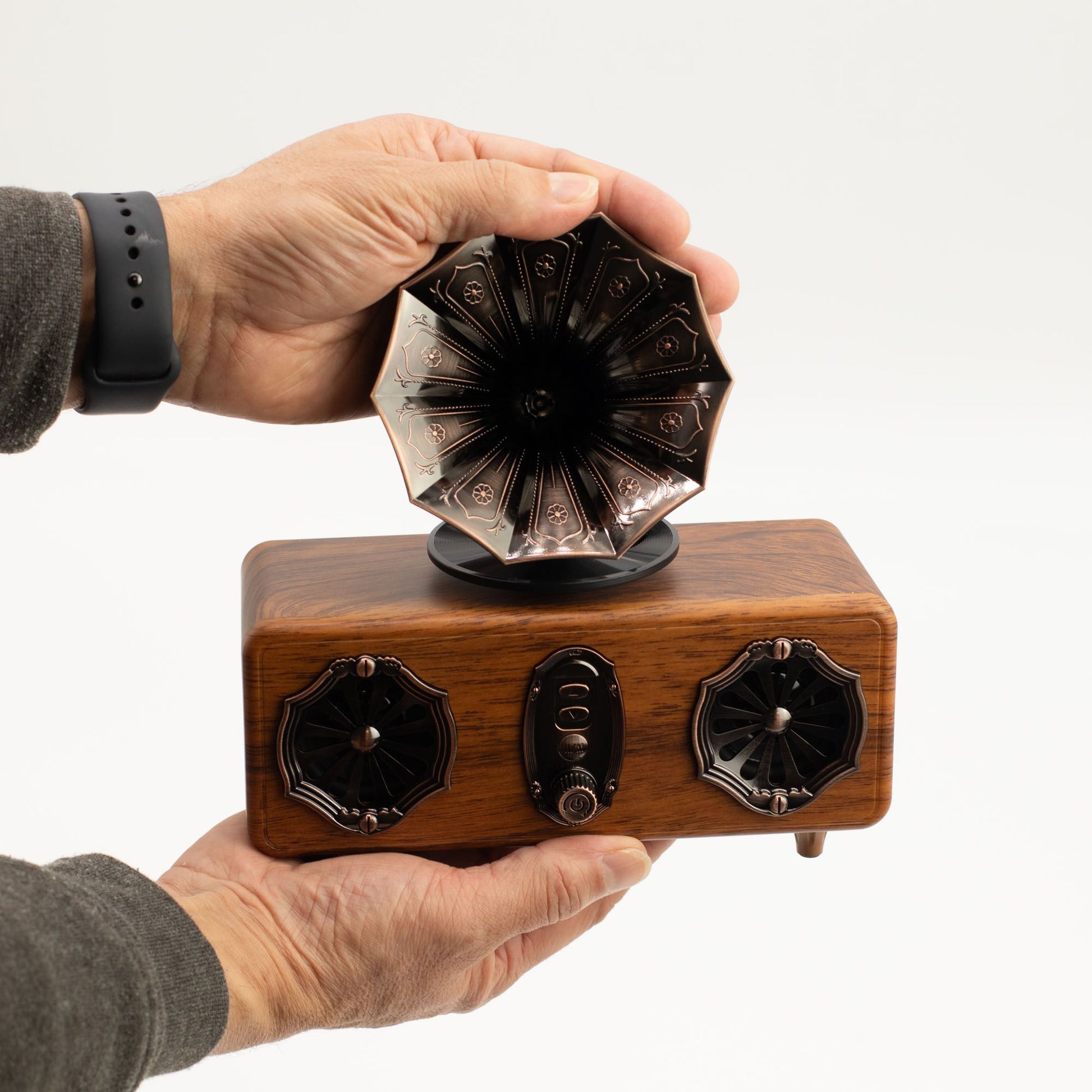 Hand holding a wooden and metal Retro mini double gramophone Bluetooth speaker against a white background