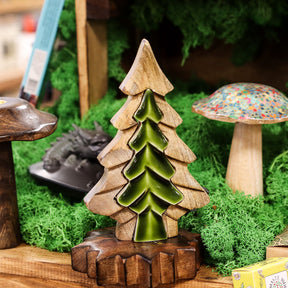 Wooden and ceramic tree figurine on a miniature landscape with a mushroom and other elements.