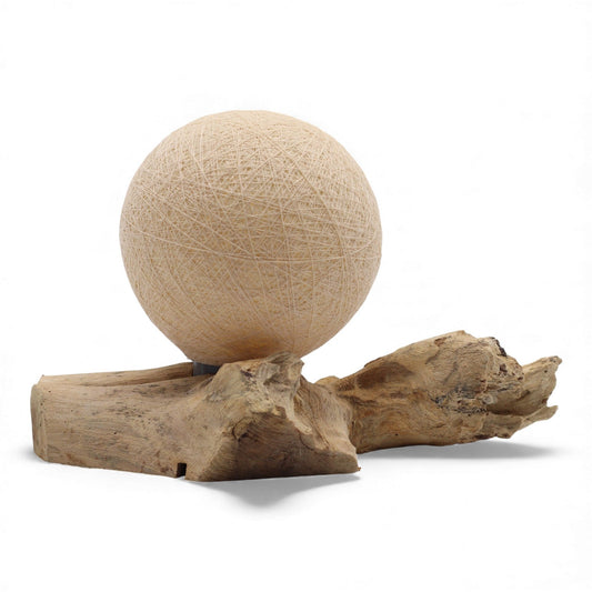 Cream cotton-wrapped sphere glowing gently atop twisted driftwood base