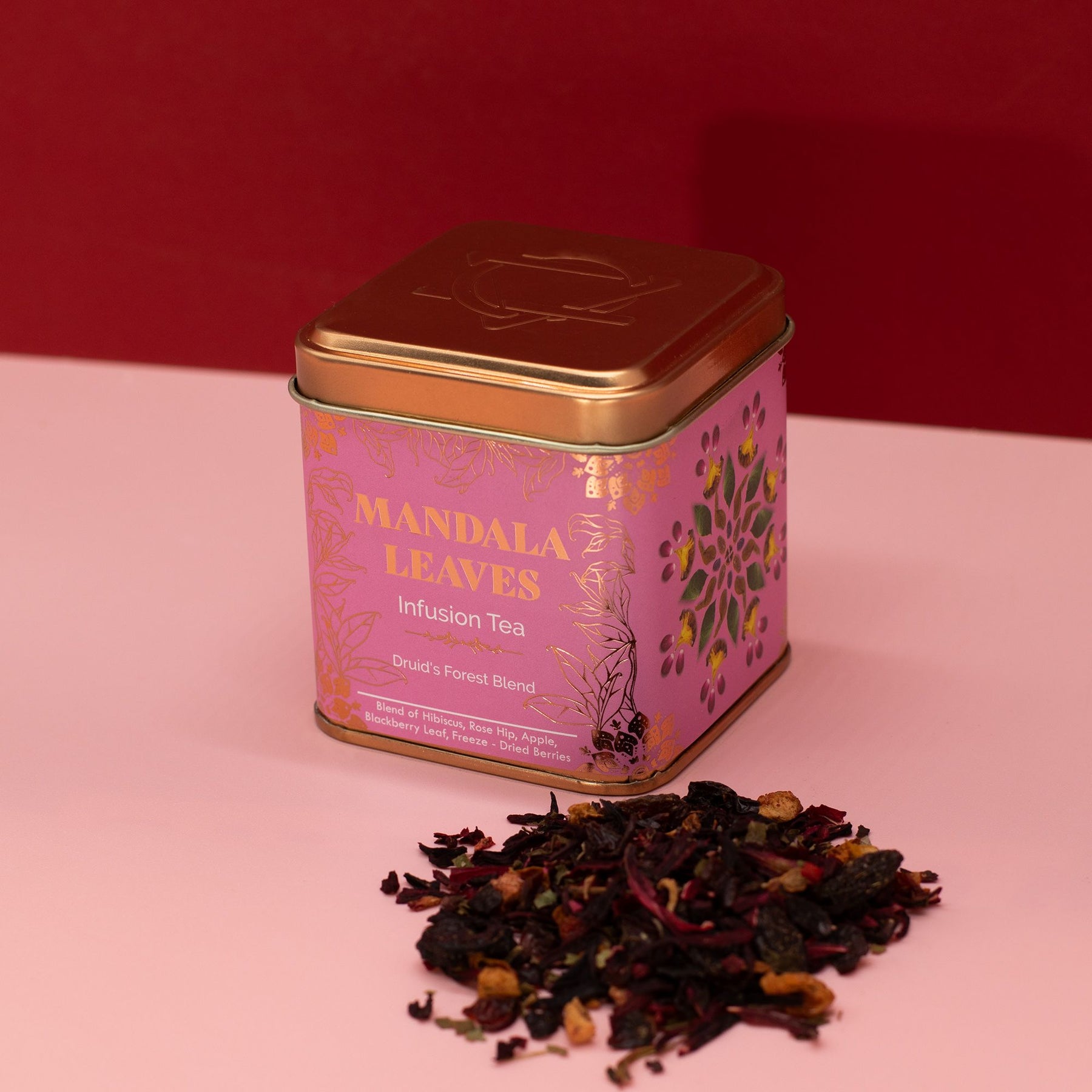 Tea tin labeled 'Mandala Leaves' with loose tea leaves on a pink background