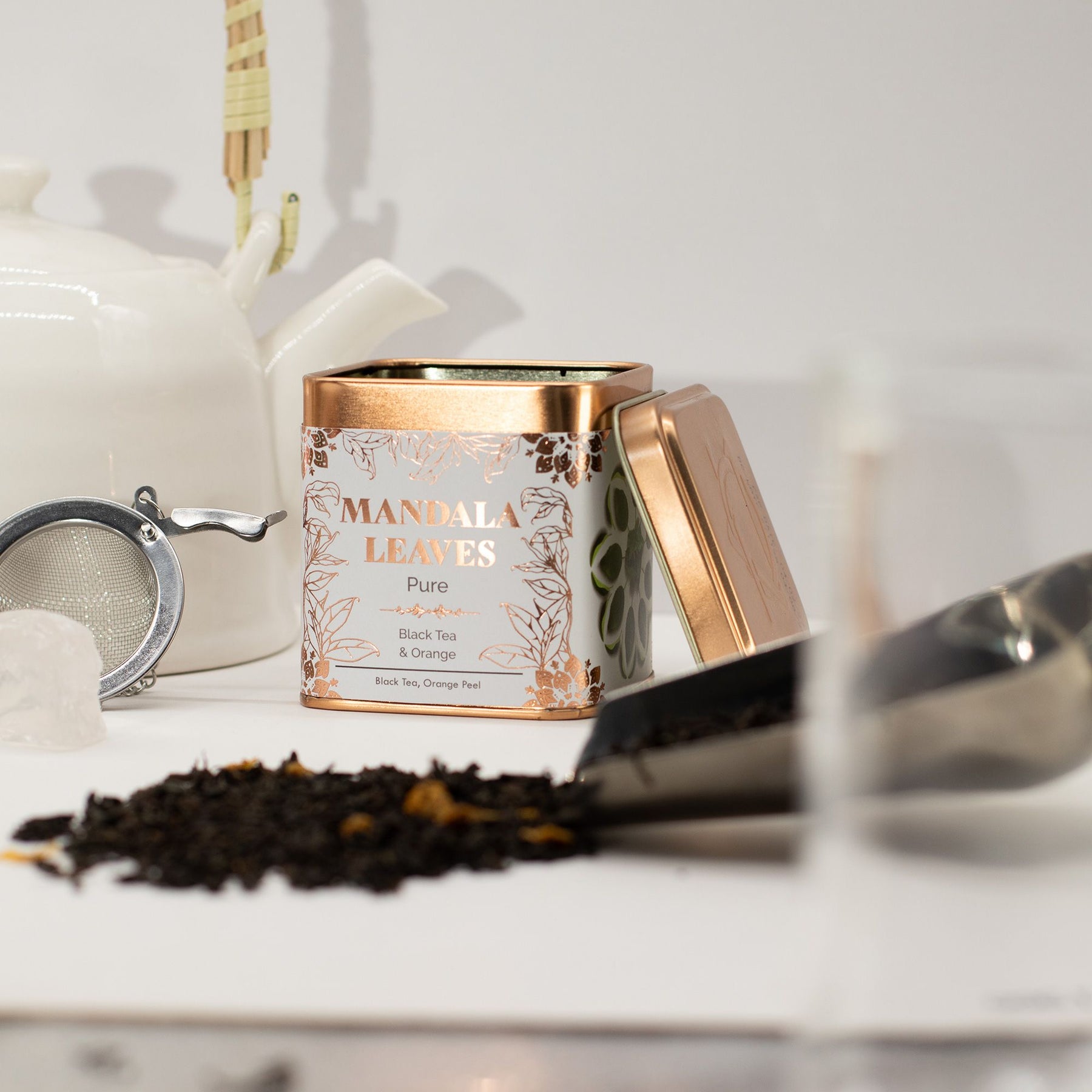 Tea canister labeled 'Mandala Leaves' with tea leaves and a teapot on a white surface.