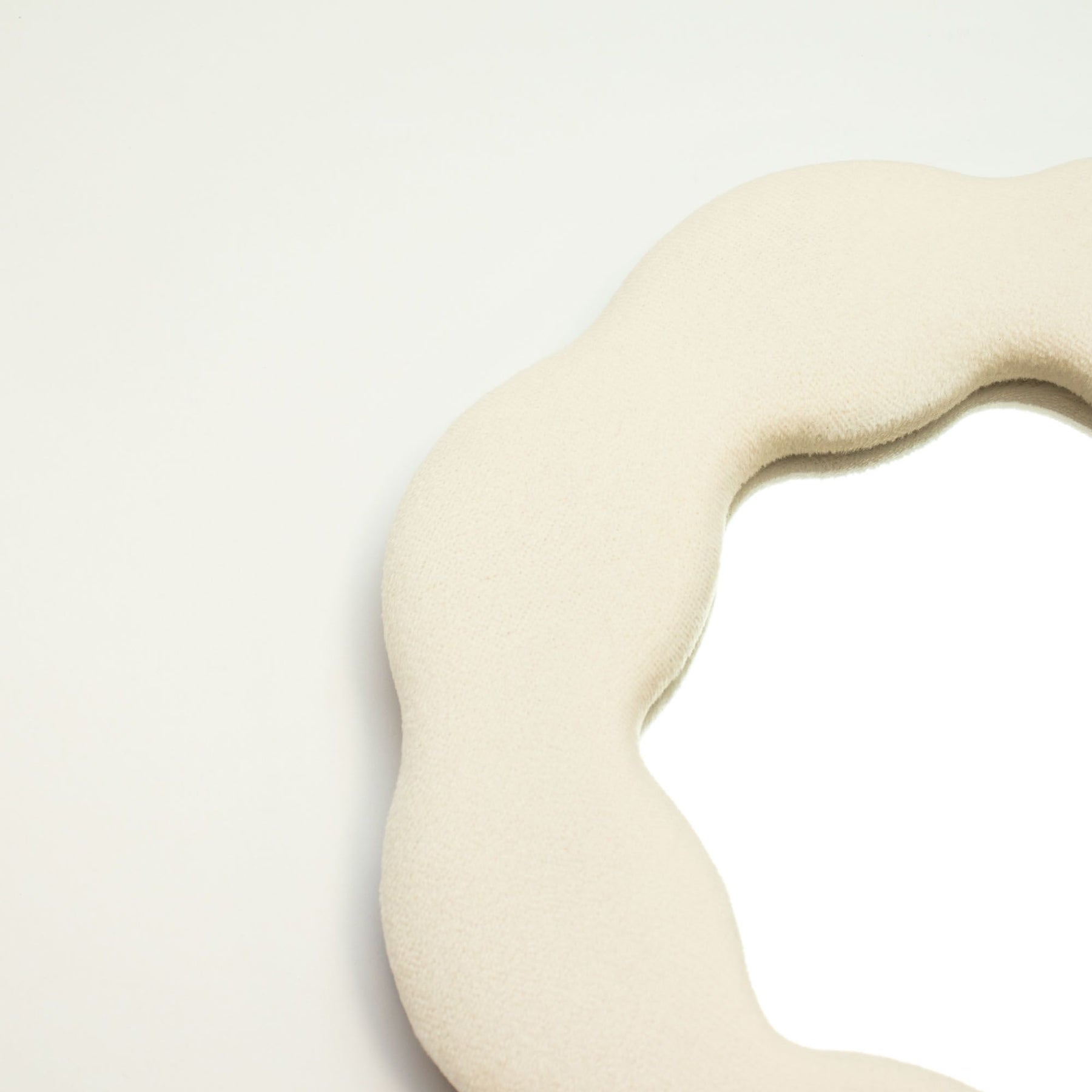 Close-up of stone-toned velvet texture on padded frame, showing plush finish and delicate flower-inspired squiggly edge detail