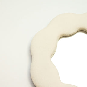 Close-up of stone-toned velvet texture on padded frame, showing plush finish and delicate flower-inspired squiggly edge detail