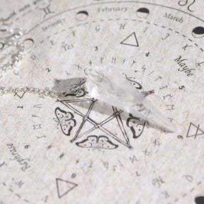 Crystal pendulum on an astrological chart with symbols and text
