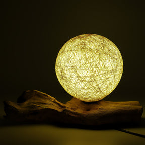 Cream cotton-wrapped sphere glowing gently atop twisted driftwood base