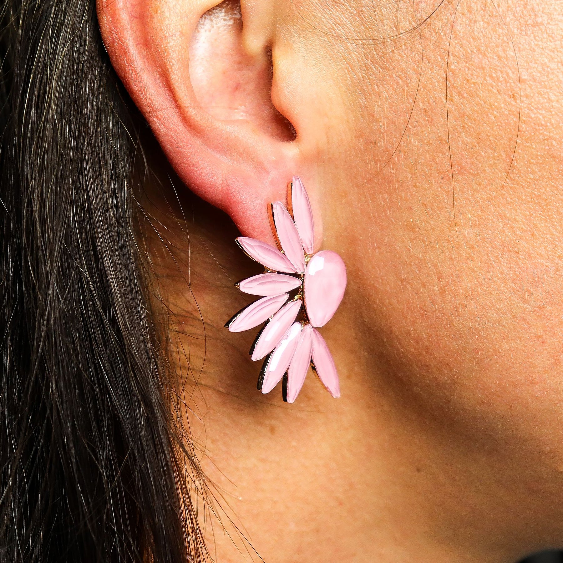 Close-up of a pink floral earring worn on an ear.