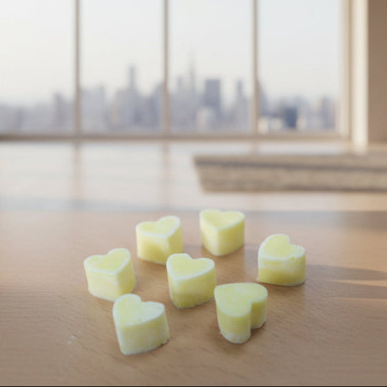 Heart-shaped Ylang Ylang & Orange Aroma Wax Melts with heart-shaped soy wax pieces on a wooden surface with a blurred cityscape in the background