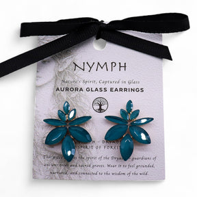 Teal green vintage glass flower earrings glowing like fresh spring leaves, styled on white linen with moss and tiny forest flowers