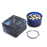 Sagittarius candle with decorative stones, packaging, and bracelet on a white background