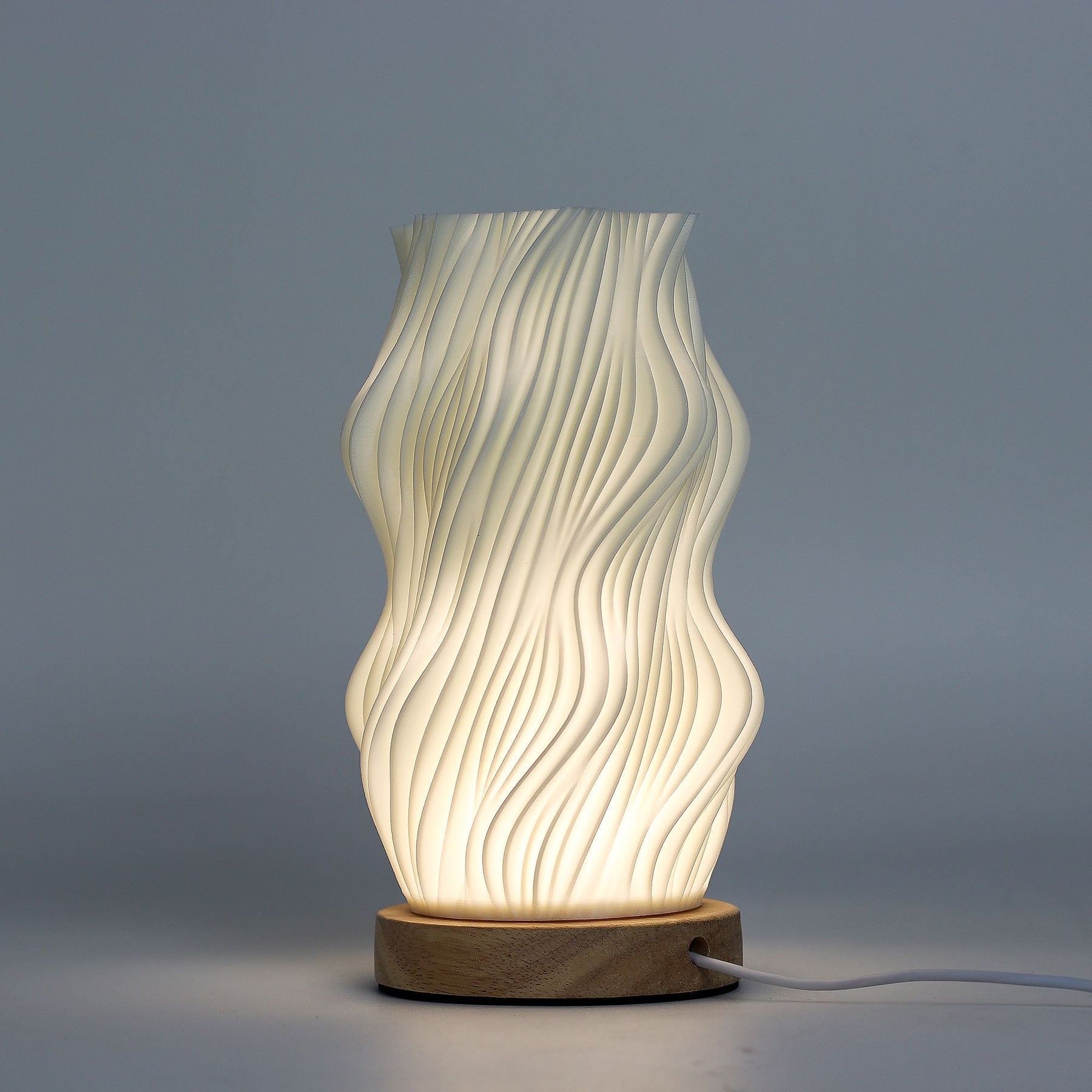 Close-up of lamp’s textured honeycomb pattern and soft diffused light, showing elegant star-like twisted shape and wooden base detail