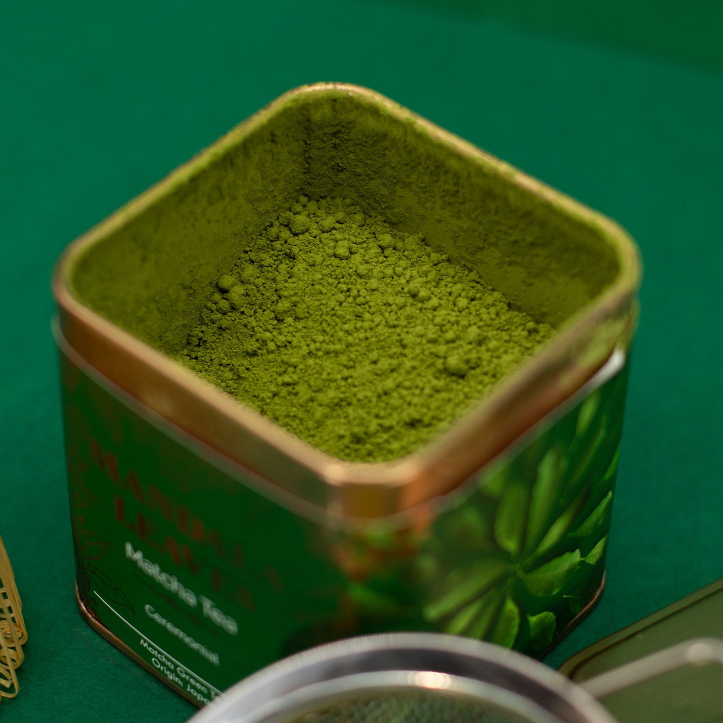 Green tea powder in a metal tin with a green background