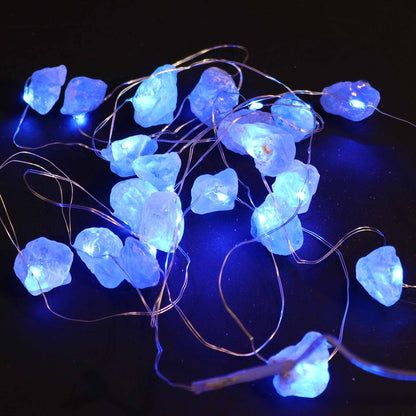 Celestite crystal fairy lights glowing soft blue in a glass jar on bedside table with moon and stars in dreamy bedroom setting