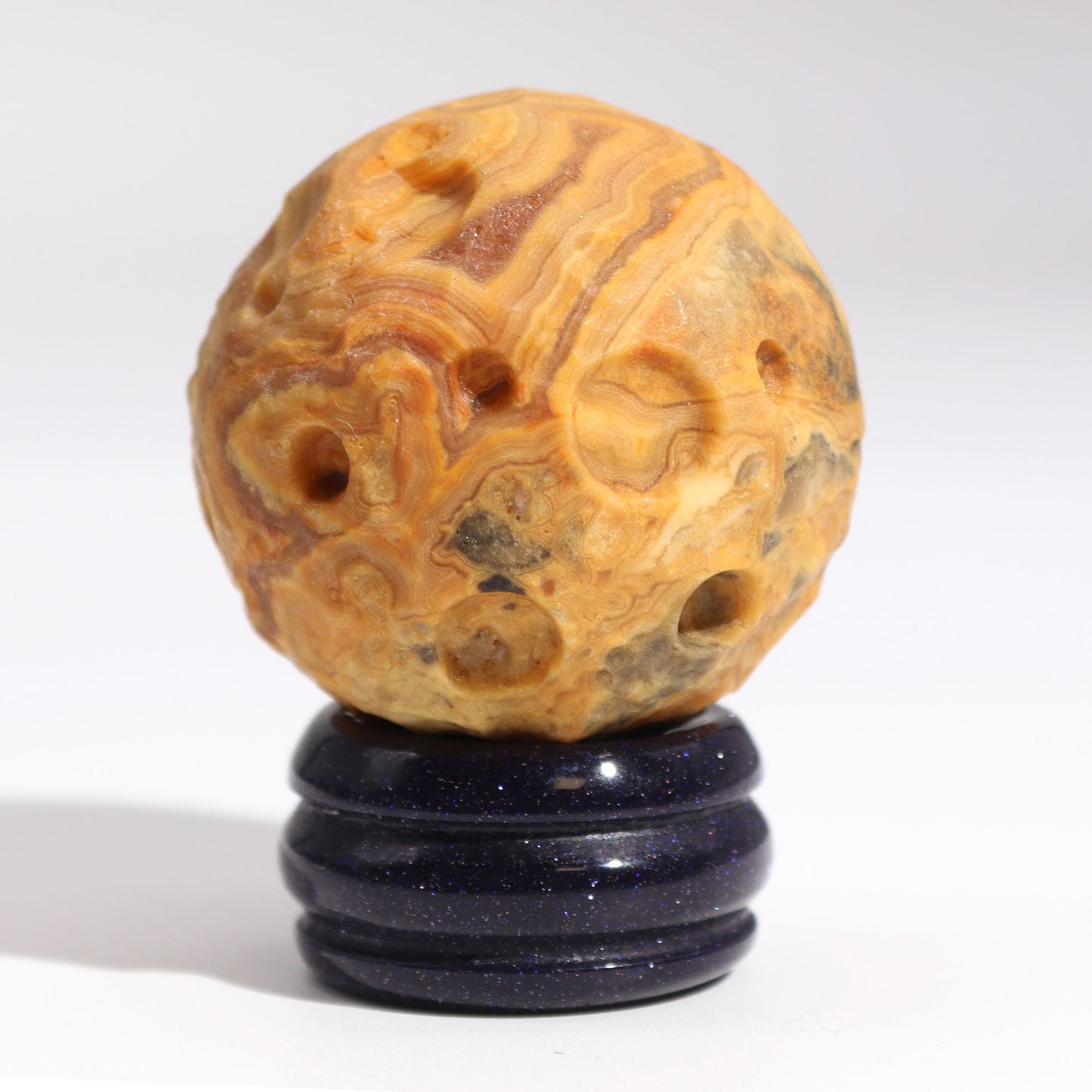 40mm swirling Crazy Lace Jasper Mercury sphere floating on shimmering goldstone ring stand, glowing against starry cosmic background