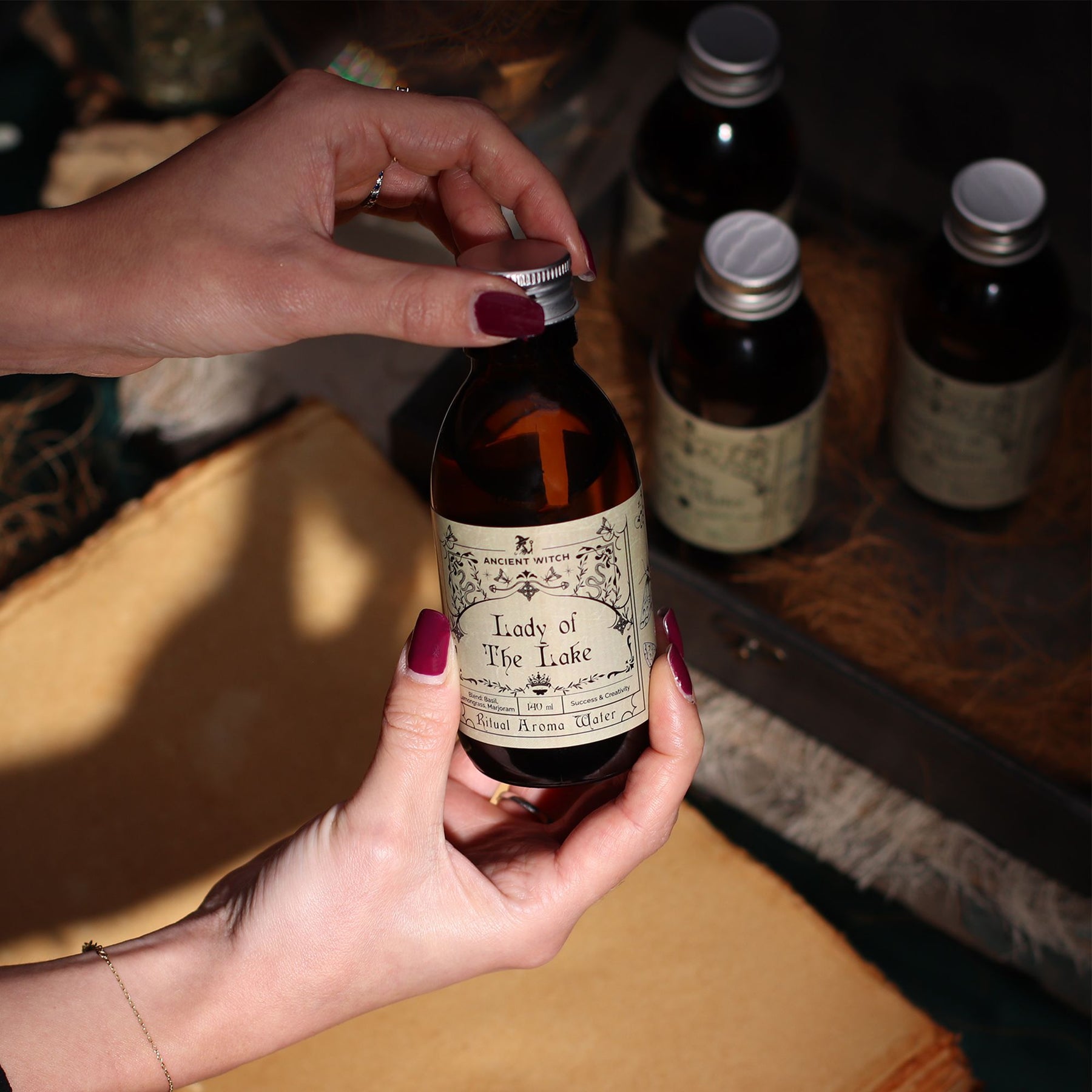 Hand holding a bottle labeled 'Lady of the Lake' with other bottles in the background.