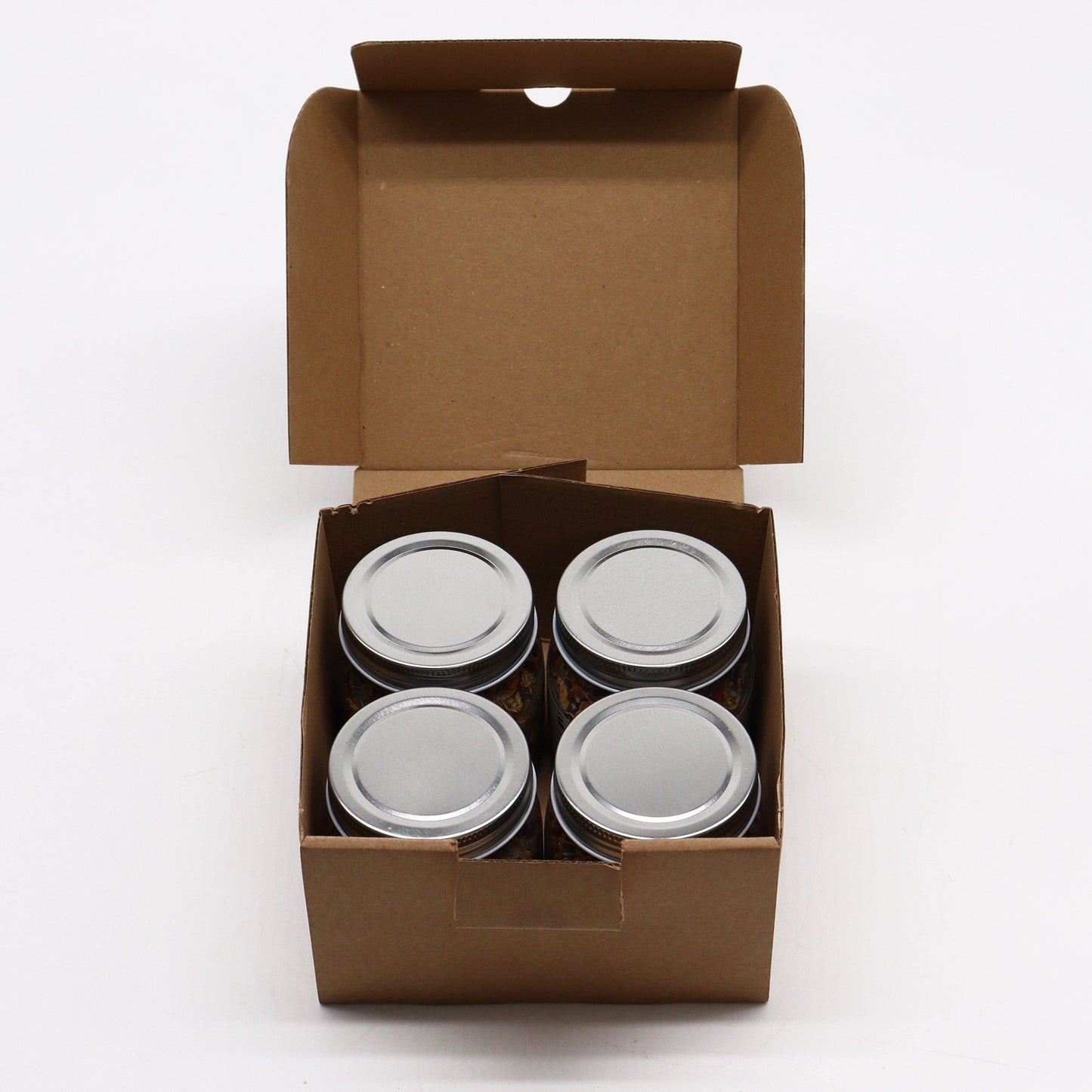 Four metal cans in a brown cardboard box on a white background