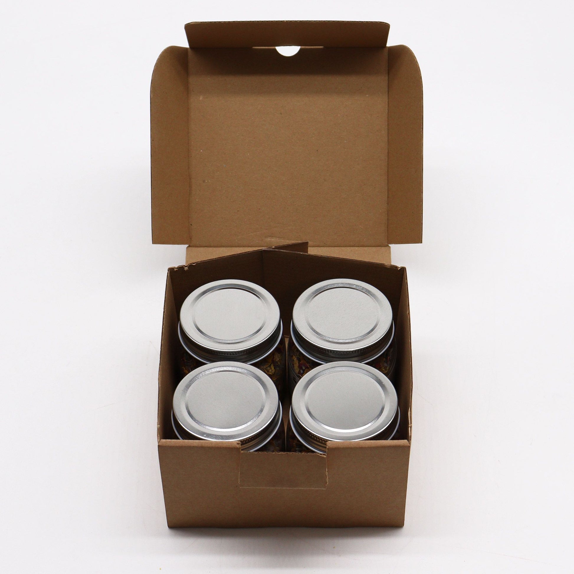 Four metal cans in a brown cardboard box on a white background