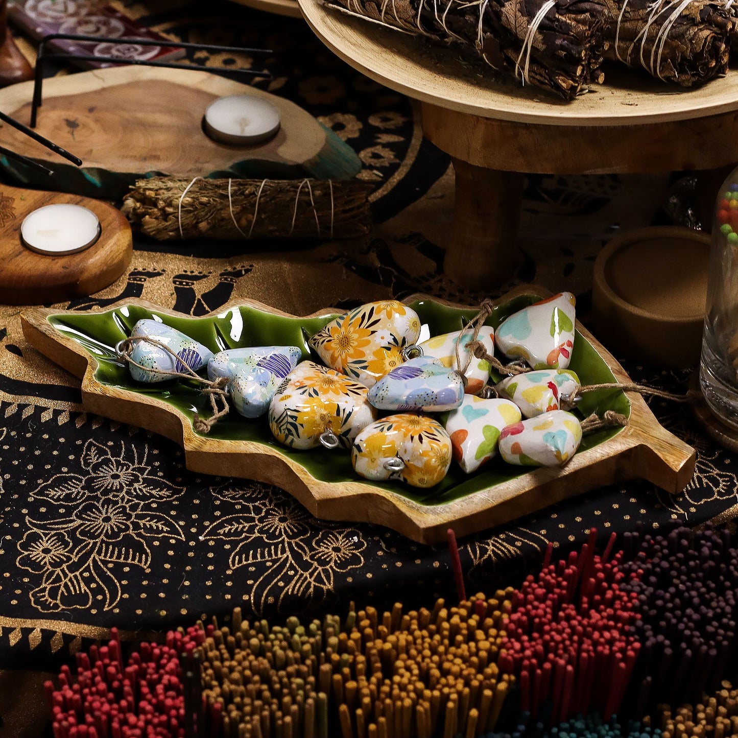 Large leaf-shaped mango wood bowl with rich green enamel inside, filled with pine cones and candles on autumn table setting