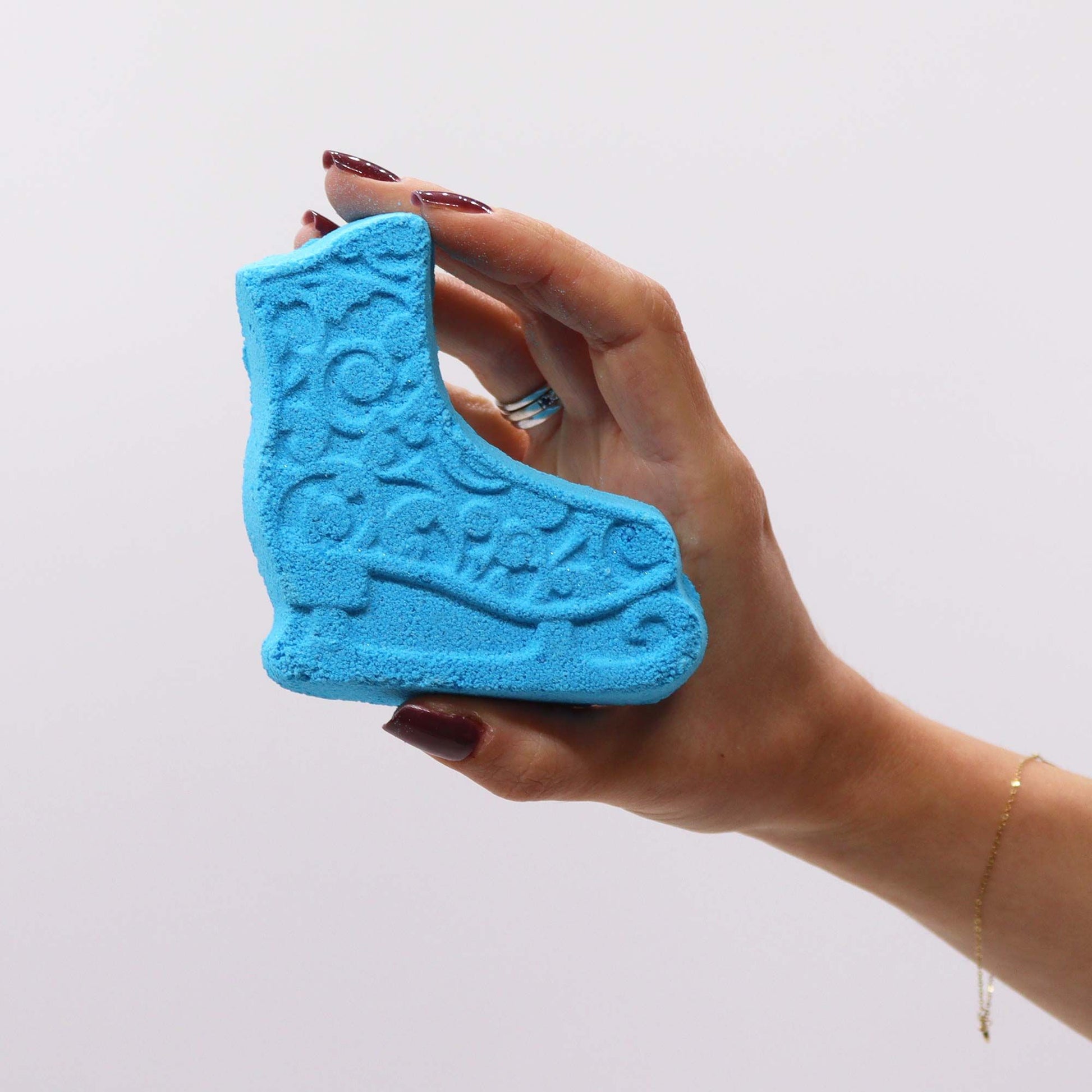 Hand holding a blue ice skate bath bomb