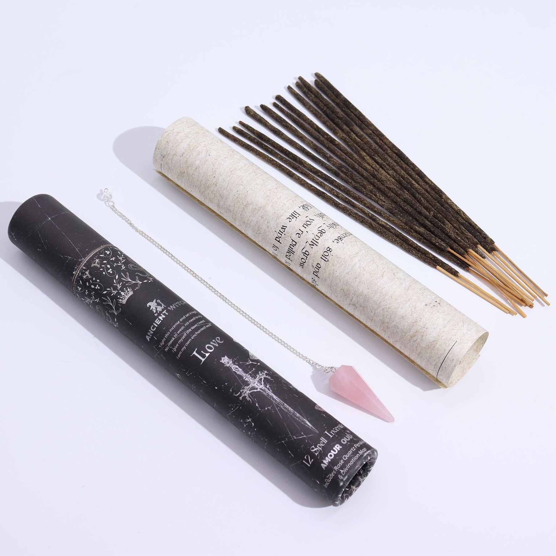 Incense sticks and pendulum with a black and a white cylindrical container on a light gray background