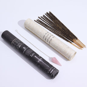 Incense sticks and pendulum with a black and a white cylindrical container on a light gray background