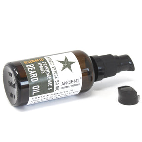 50ml amber glass bottle of Nordic Spruce Beard Oil with elegant dropper, surrounded by fresh spruce needles, frankincense resin and apricot kernels