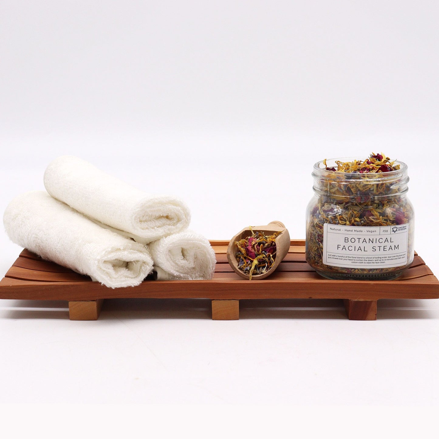 250g jar of dried lavender buds, rose petals, chamomile & calendula flowers spilling onto white marble with steaming bowl in soft spa setting