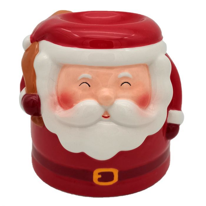 Smiling Santa Claus ceramic oil burner with glowing tealight inside, wax melting in dish, surrounded by Christmas lights and pine branches