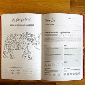 Elegant white wellness journal with rose gold foil Tree of Life, open to mood tracker and affirmation pages, styled with crystals, rose quartz and candle