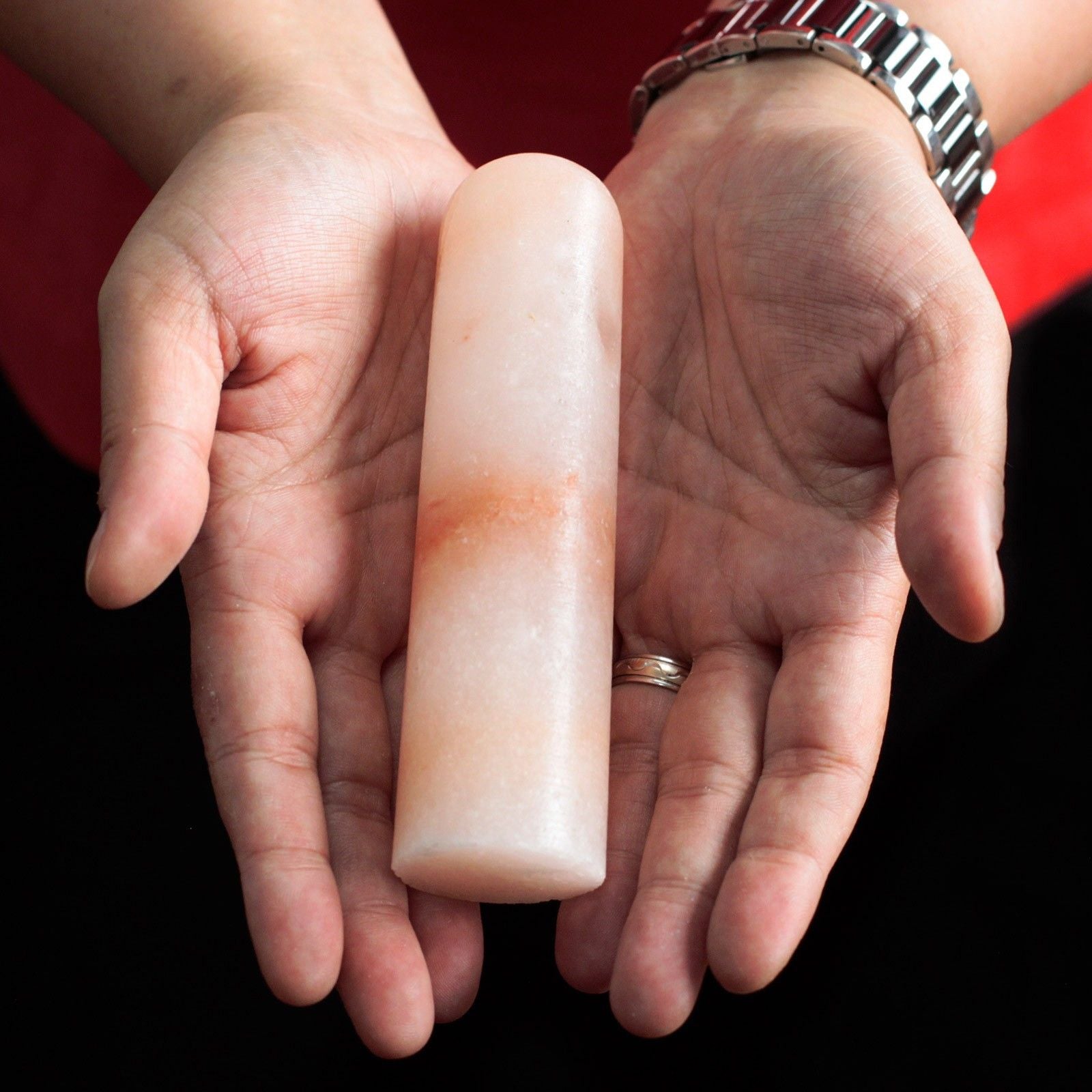 Two hands holding Himalayan Stick Deodorant Stone against a black background