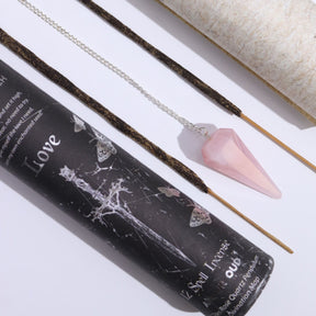 Incense sticks and pendulum with a black container labeled 'Love' on a white background