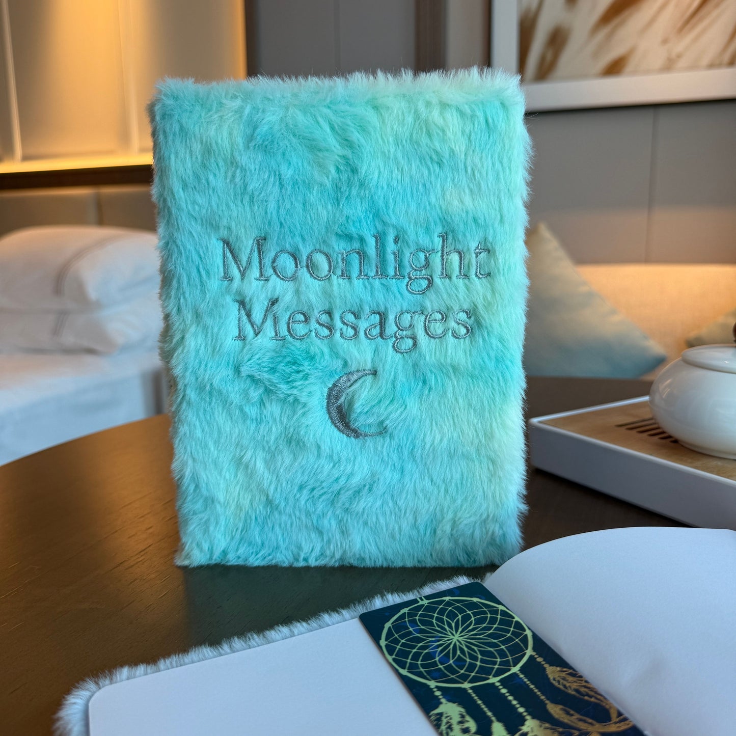 Turquoise fluffy notebook titled 'Moonlight Messages' on a table