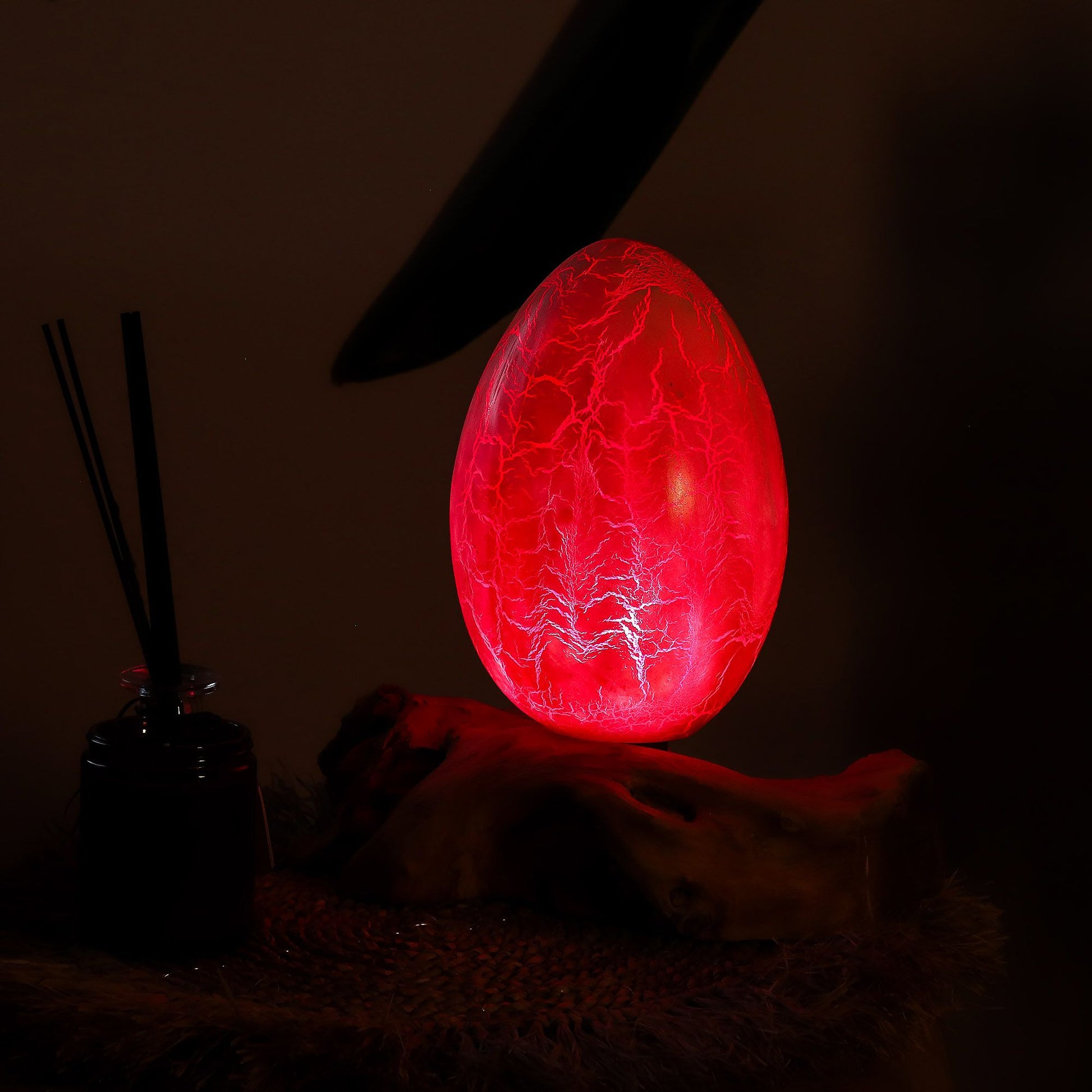 Vivid orange crackle egg shade glowing like molten fire atop twisted driftwood base