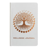Elegant white wellness journal with rose gold foil Tree of Life, open to mood tracker and affirmation pages, styled with crystals, rose quartz and candle