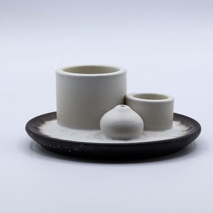 Set of ceramic containers on a black tray with a white background