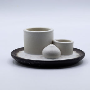 Set of ceramic containers on a black tray with a white background