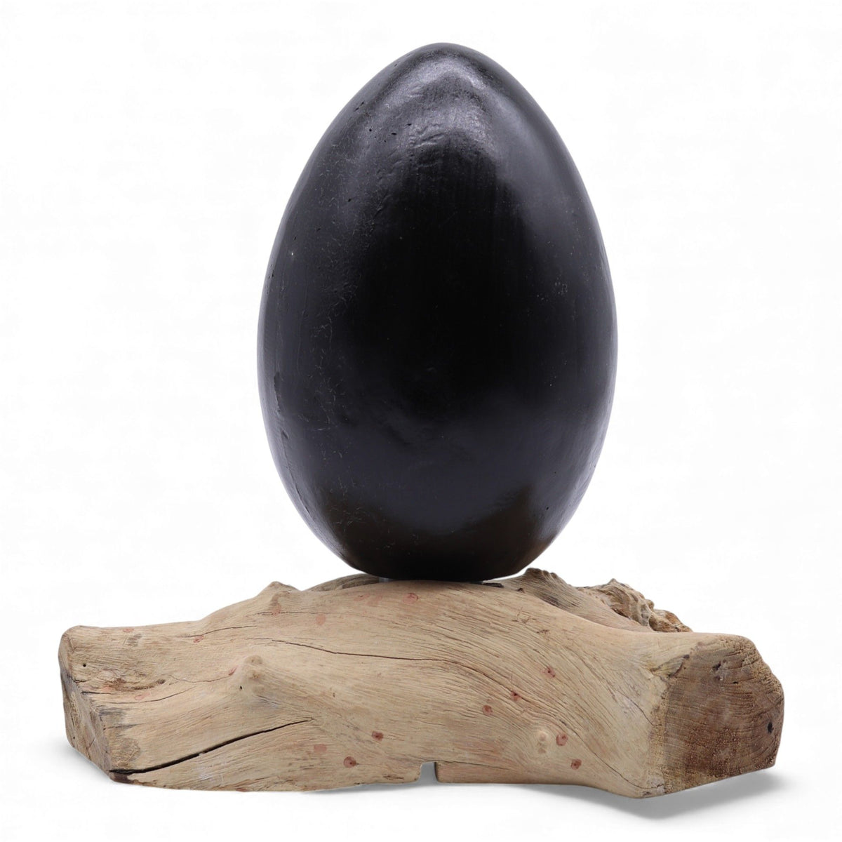 Grey egg shade glowing like molten lava atop twisted driftwood base, styled on dark console