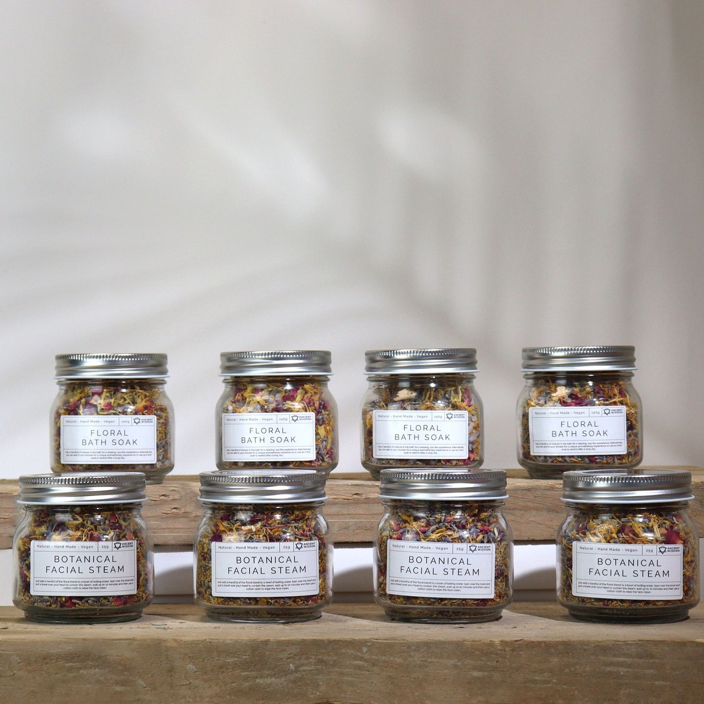 Set of eight jars labeled 'Floral Bath Soak' on a wooden surface with a neutral background