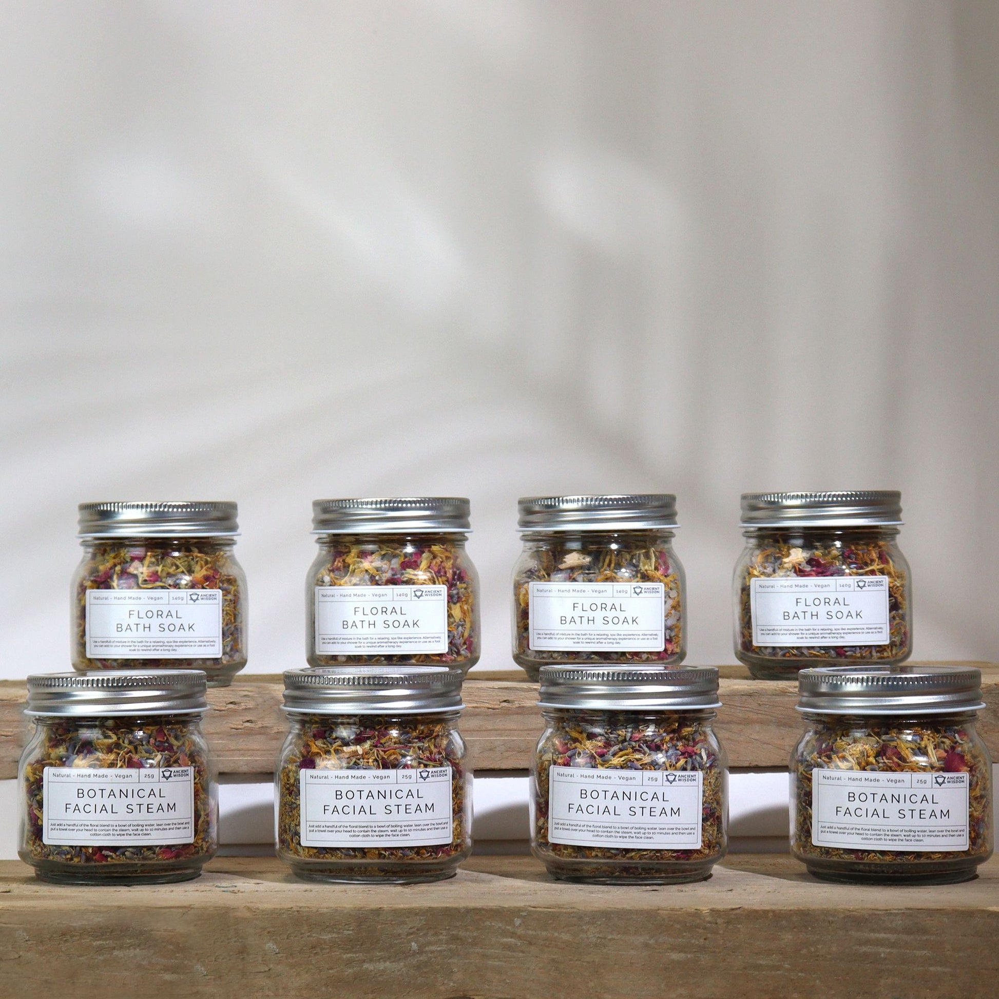 Set of eight jars labeled 'Floral Bath Soak' on a wooden surface with a neutral background