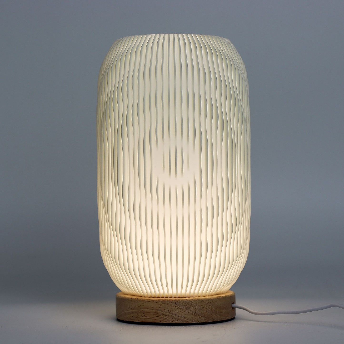 Close-up of lamp’s textured honeycomb pattern and soft diffused light, showing elegant twisted modern shape and wooden base detail