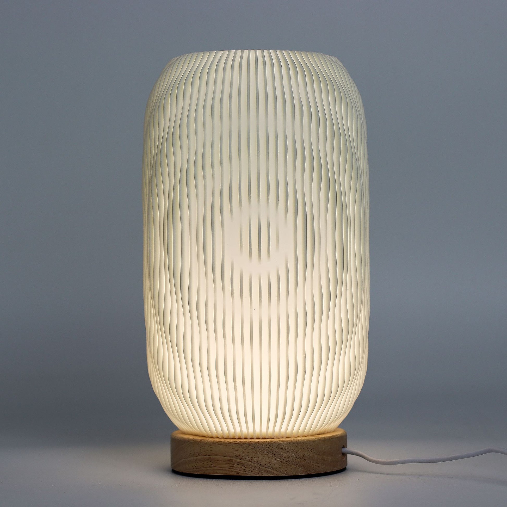 Close-up of lamp’s textured honeycomb pattern and soft diffused light, showing elegant twisted modern shape and wooden base detail