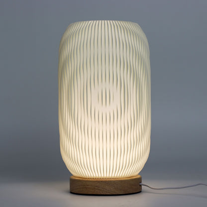 Close-up of lamp’s textured honeycomb pattern and soft diffused light, showing elegant twisted modern shape and wooden base detail