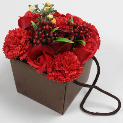 Bouquet of red flowers in a brown paper bag with a string handle on a white background
