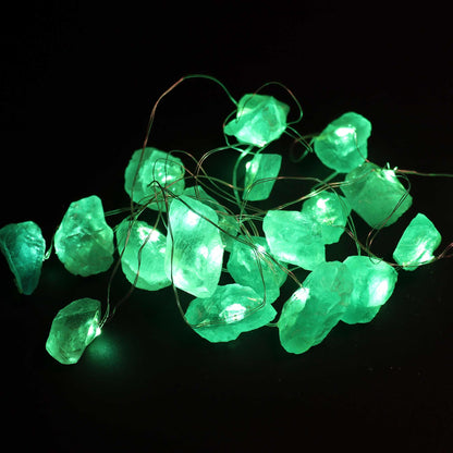 Crystal jade fairy lights glowing soft green in glass bowl on wooden desk with bamboo, coins and prosperity crystals in calming setting