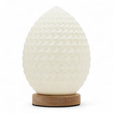 Teardrop New Wave USB lamp with textured honeycomb surface, warm glow on 3rd brightness setting, placed on wooden base