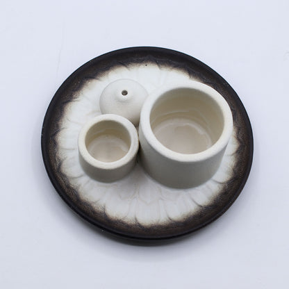 Set of ceramic containers on a textured black base with a white background
