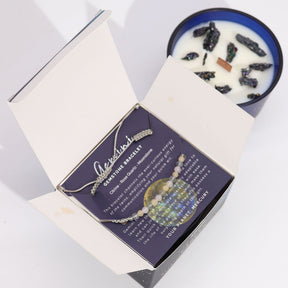 Jewelry set with necklace and bracelet on a card, next to a candle in a box.