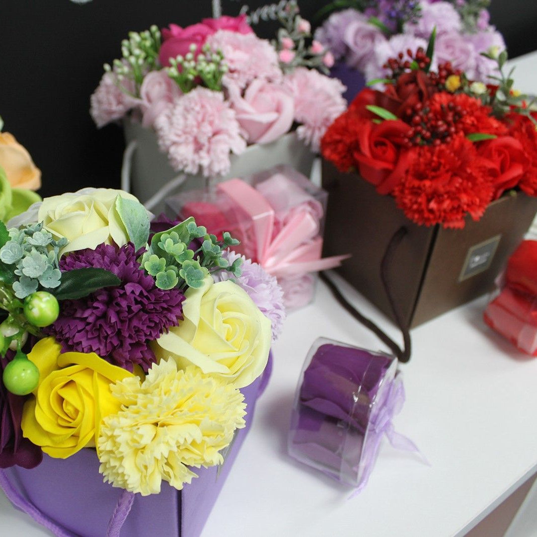 Colorful soap flower arrangements in boxes on a table with a blackboard background